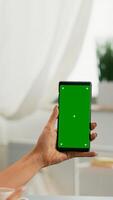 Over shoulder of business woman using isolated smartphone with mock up green screen chroma key sitting on table desk, while talking with her friends during online videocall sitting on office desk photo