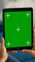 Close up of business woman hands holding tablet computer with mock up green screen chroma key display sitting on sofa. Freelancer using isolated touchscreen device for social networks browsing photo
