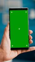 Pov of business man hands holding professional smartphone in portrait vertical mode with mock up green screen chroma key display. Freelancer using isolated phone for browsing social networks photo