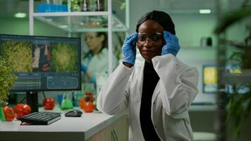 Portrait of african biologist in white coat looking into camera working in microbiology laboratory. Specialists team researching genetic mutation developing dna GMO biology test photo