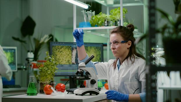 Biologist scientist looking at test sample using microscope for chemical expertise. Chemist researcher woman working in pharmaceutical laboratory discovering genetic mutation on plants photo