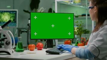 Scientist woman working on computer with mock up green screen chroma key with isolated display observing chemical test. Pharmaceutical researcher working in microbiology laboratory photo