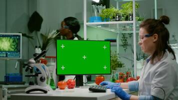 Pharmaceutical researcher looking at computer with mock up green screen chroma key with isolated display typing on keyboard medical expertise. Biologist working in microbiology laboratory photo
