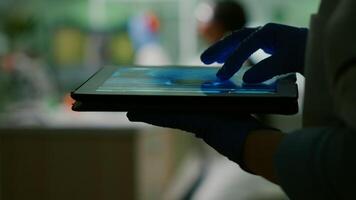 Chemist scientist woman checking dna sample test using tablet while her collegue typing microbiology experiment on computer in background. Medical team working in microbiology laboratory photo