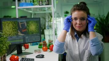 Portrait of biologist woman putting medical glasses looking into camera while sitting at table in pharmaceutical laboratory. Specialists researching genetic mutation developing dna test photo