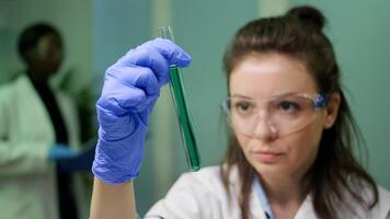 Closeup of scientist woman looking at test tube with dna sample examining for microbiology experiment. Researcher biologist working in agriculture laboratory developing gmo expertise on plants photo