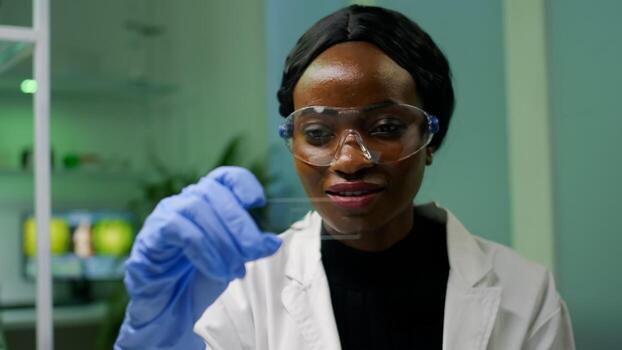African botanist woman looking at genetic test sample for biological experiment. Pharmaceutical scientist analyzing organic agriculture in microbiology scientific lab working at biochemistry expertise photo