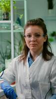 Portrait of chemist woman in white coat working in pharmaceutical laboratory. Biologist scientific analyzing organic plants genetically modified for engineering medical experiment, GMO scince experiment photo