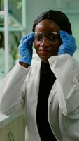 Portrait of african biologist in white coat looking into camera working in microbiology laboratory. Specialists team researching genetic mutation developing dna GMO biology test photo