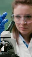 Closeup of scientist woman looking at test sample of leaf analyzing for biological experiment with organic plants. Biologist specialist discovering organic gmo plants while working in microbiology lab photo