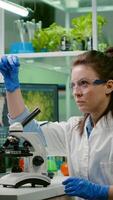 Biologist scientist looking at test sample using microscope for chemical expertise. Chemist researcher woman working in pharmaceutical laboratory discovering genetic mutation on plants photo