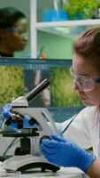Scientist researcher examining genetically modified green leaf under microscope. Biologist engineering observing organic gmo plants while examining in microbiology food laboratory photo