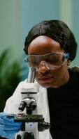 Portrait of scientist taking leaf sample with micropipette putting on slide under microscope for medical experiment. Chemist analyzing organic agriculture plants in microbiology scientific laboratory photo