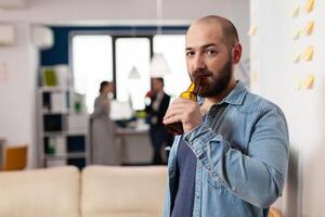 Man drinking bottle of beer after work meeting with colleagues for fun enjoyment. Cheerful celebration with coworkers at office while eating and drinking alcohol. Happy friends partying photo