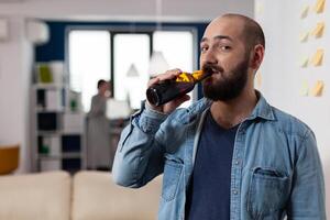 Man drinking bottle of beer after work meeting with colleagues for fun enjoyment. Cheerful celebration with coworkers at office while eating and drinking alcohol. Happy friends partying photo