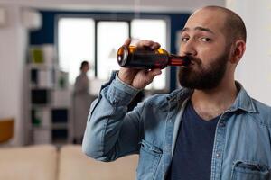 Portrait of caucasian man with bottle of beer at after work drinks meeting with coworkers. Person having fun with friends in business office, enjoying party celebration with food and alcohol. photo