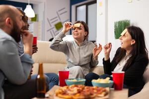 Businesspeople playing charades game and having fun together at office party, using sticky notes on forehead for guessing activity. Man and women enjoying drinks after work hours. photo