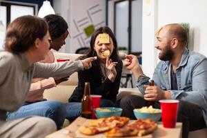 Man and women enjoying guessing game with sticky notes, playing charades together at drinks celebration after work hours. Office workmates having fun with patnomime activity at party. photo