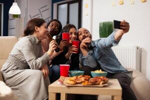 Business people taking pictures on smartphone at office party with drinks and snacks after work hours. Colleagues using mobile phone to take selfies and make memories at fun celebration. photo