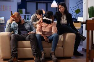 Disappointed woman with vr headset losing at games on tv console, using virtual reality glasses and controller to play for entertainment. Office colleagues meeting for drinks after hours. photo