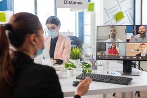 Businesswoman during remove conference on computer wearing face mask as safety precaution during global pandemic with covid19 flu in new normal workplace. Online web internet virtual videocall photo