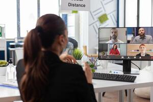 Businesswoman discussing with remote business team during online videocall meeting conference on computer working at management strategy in startup company office. Teleconference call on screen photo