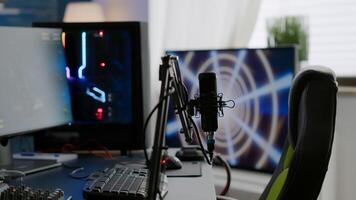 Game loading on display of RGB professional powerful computer and stream chat is prepared for virtual tournament. Streaming professsional microphone in empty gaming home studio with neon lights. photo