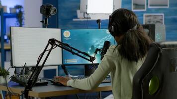 Black player wearing headphones talking with other players chatting while playing professional shooter games in online tournament. Gamer making online videogames with new graphics on powerful computer photo