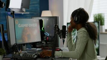 Back shot of afro american esport streaming losing virtual competition wearing headphones. Professional gamer streaming online games with new graphics on powerful computer. photo