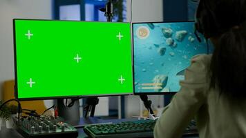 Black woman gamer streaming online videogame on powerful computer with green screen mock up chroma key display. Cyber player using professional pc with isolated desktop playing shooter game in headset photo
