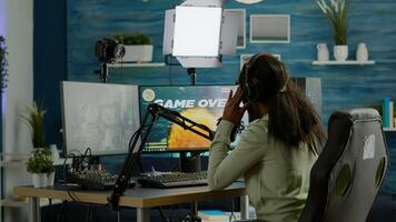Afro streamer losing online championship being disappointed for space shooter game over. Pro gamer streaming online games with new graphics, talking on stream chat using RGB powerful computer. photo