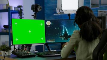 Pro african woman player gaming on powerful computer with green mock up chroma key screen while streaming online competition. Gamer using pc with greenscreen isolated desktop streaming shooter games photo