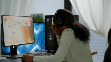 Upset professional black woman gamer wearing headset losing space shooter game in cybersport competition. Tired pro cyber player gaming online games on powerful personal computer with RGB lights photo