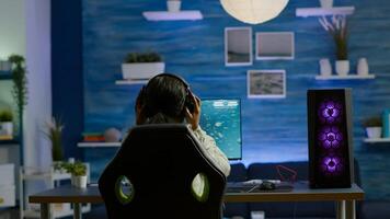 African player sitting on gaming chair with headset playing online space shooter videogames using RGB keyword. Pro cyber streaming online game new graphics using powerful personal computer photo