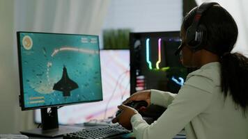 Pro african gamer playing online space shooter game on powerful computer using wireless controller and headset. Competitive cyber player woman performing videogame tournament use professional joystick photo