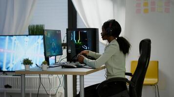 Black woman gamer winning videogames using professional wireless controller and headset playing on powerful computer. Excited online streaming cyber performing during gaming tournament using joystick. photo