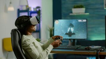 Black woman gamer playing game at powerful computer late night wearing vr headset. Excited player using wireless controller for virtual tournament gaming space shooter at home photo