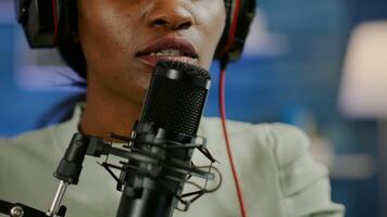 Close up of african influencer answering questions while talking into microphone for listeners. Speaking during livestreaming, blogger discussing in podcast wearing headphones. photo