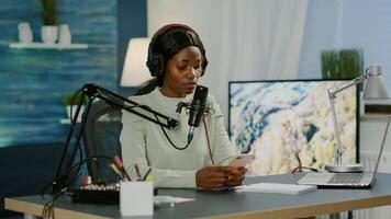 African blogger woman reading messages on smartphone recording for her blog in home studio. On-air online production internet broadcast show host streaming live content for social media photo