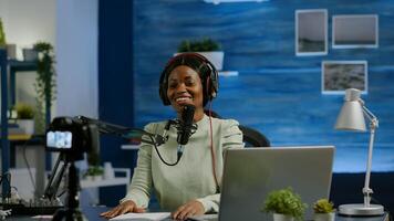 Woman african vlogger recording to camera tutorial about lifestyle in home podcast studio during livestreaming. On-air online production internet broadcast show host streaming live content for social media photo
