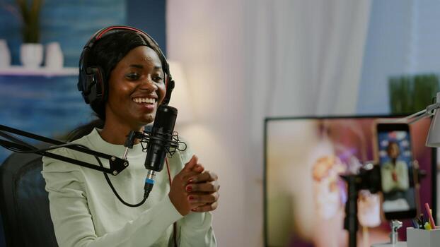 African vlogger recording blog using smartphone with modern equipment in home studio podcast. Media star looking at camera for broadcast and having fun using technology to connect with audiences photo