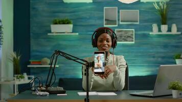 Black influencer in entertainment industry talking and checking sound during broadcast from home studio. On-air online production internet podcast show host streaming live content for social media photo