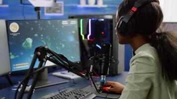 Pro cyber black woman streaming videogame, reading on stream chat and playing space shooter on RGB powerful computer. Streamer sitting on gaming chair playing game during online esports tournament. photo