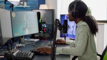 Competitive black gamer with headphones using stream chat on RGB powerful computer playing online shooter game late at night. Virtual online streaming cyber performing in gaming tournament photo