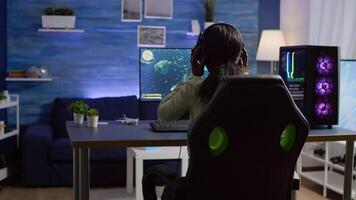 Pro gamer playing shooter game at gaming home studio using RGB mouse keyboard on powerful computer. Virtual online streaming setup with neon lights cyber performing during game tournament photo
