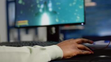 Close up of african woman cyber moving professional mouse with RGB playing space shooter game. Player using powerful gaming computer in home studio of esport videogame typing at keypad photo