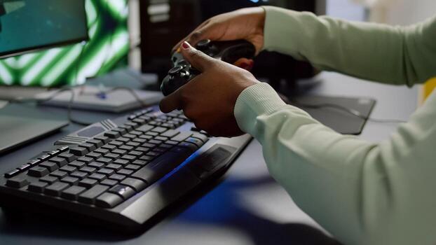 Close-up of professional cyber gamer holding joystick playing space shooter game. Pro player use RGB equipment during gaming tournament late at night in home studio using wireless controller photo