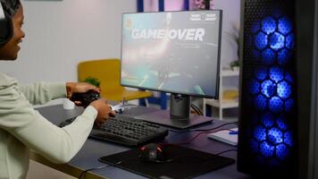 Game over for woman african streamer playing space shooter games at home using professional wirelles controller. Pro gamer talking into microphone on streaming chat during online tournament photo