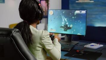 Back shot of pro black woman streamer winning graphics cyber space shooter games using wireless joystick. Gamer performing on powerful pc talking with players on chat open during competition photo