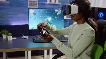 Black woman videogame player with vr goggles raising hands holding joystick after winning space shooter competition. Professional pro cyber playing online game with new graphics on powerful computer photo